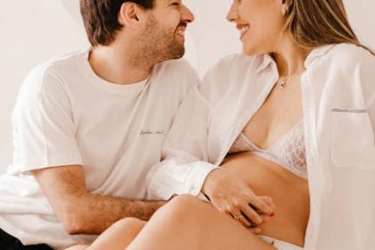 A couple sitting comfortably on a bed, sharing a loving gaze in a bright room, radiating happiness.