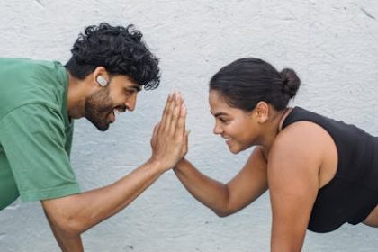 Fit couple enjoys a workout session with high fives, promoting fitness and partnership.