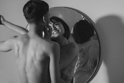 Une photographie romantique en noir et blanc d'un couple partageant un moment intime, reflété dans un miroir.
