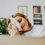 Happy woman with dollar bills, symbolizing financial success and fulfillment.