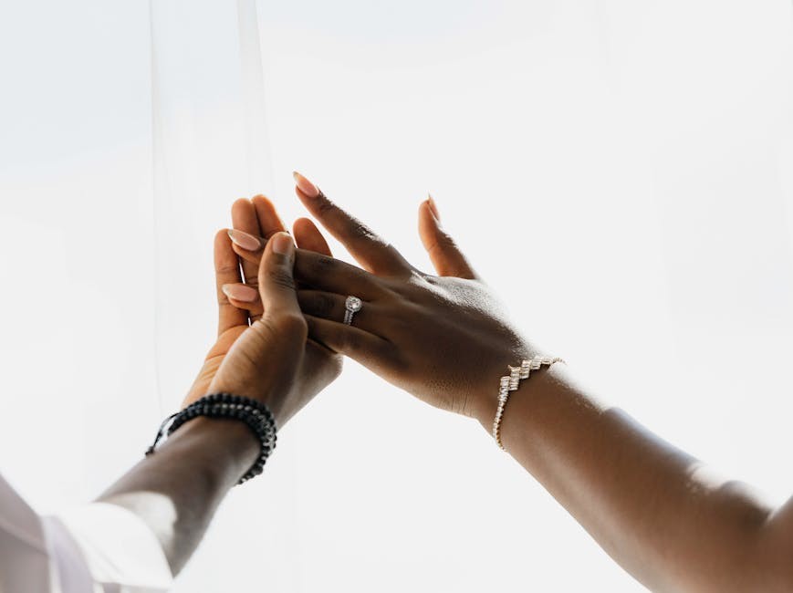 Gros plan sur des mains ornées d'élégantes alliances et de bijoux, symbolisant l'amour et l'union.