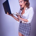 Young woman in a studio showing surprise while using a laptop. Ideal for technology and lifestyle themes.