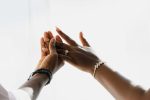 Gros plan sur des mains ornées d'élégantes alliances et de bijoux, symbolisant l'amour et l'union.