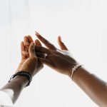 Gros plan sur des mains ornées d'élégantes alliances et de bijoux, symbolisant l'amour et l'union.