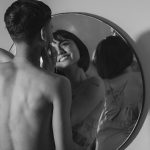 Une photographie romantique en noir et blanc d'un couple partageant un moment intime, reflété dans un miroir.