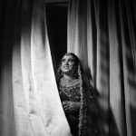 Magnifique portrait en noir et blanc d'une mariée indienne en tenue traditionnelle, près d'un rideau.