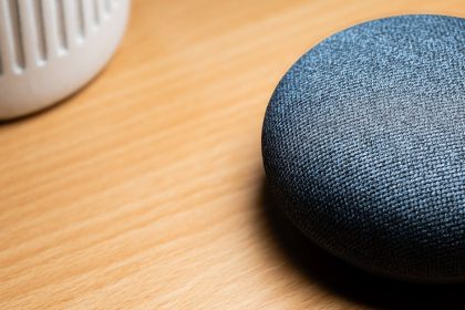 Gros plan d'une enceinte connectée posée sur une table en bois, révélant les détails de sa texture.