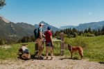 Un couple profite d'une randonnée avec son chien dans un magnifique paysage de montagne par une journée ensoleillée.