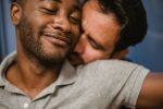 Gros plan de deux hommes partageant une étreinte affectueuse, exprimant l'amour et la connexion.