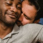Gros plan de deux hommes partageant une étreinte affectueuse, exprimant l'amour et la connexion.