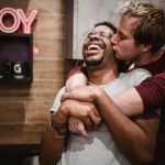 Moment réconfortant d'amour et de bonheur entre un couple gay interracial joyeux s'enlaçant dans un cadre confortable.
