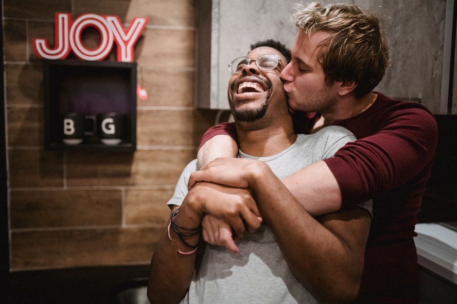 Moment réconfortant d'amour et de bonheur entre un couple gay interracial joyeux s'enlaçant dans un cadre confortable.