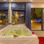 Découvrez une relaxation ultime dans un jacuzzi intérieur de luxe orné de pétales et de bougies d'ambiance, parfait pour une retraite sereine.