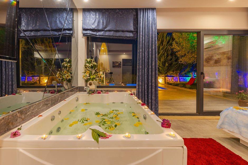 Découvrez une relaxation ultime dans un jacuzzi intérieur de luxe orné de pétales et de bougies d'ambiance, parfait pour une retraite sereine.