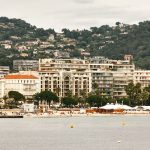 Vue panoramique d'un complexe hôtelier de luxe sur le front de mer de Cannes, mettant en valeur une architecture élégante sur fond de collines luxuriantes.