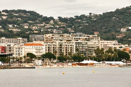 Vue panoramique d'un complexe hôtelier de luxe sur le front de mer de Cannes, mettant en valeur une architecture élégante sur fond de collines luxuriantes.