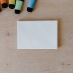 Vue de dessus de tubes de peinture colorés et d'une toile vierge sur une surface en bois.