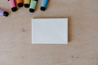 Vue de dessus de tubes de peinture colorés et d'une toile vierge sur une surface en bois.