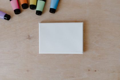 Vue de dessus de tubes de peinture colorés et d'une toile vierge sur une surface en bois.